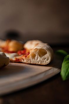 two pieces of pizza sitting on top of a white plate next to green leafy leaves