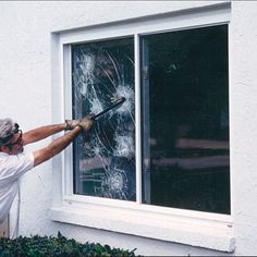 a man is holding a window pane and looking at the shattered glass in front of him