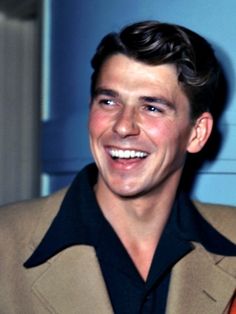 a smiling man in a tan jacket and black shirt