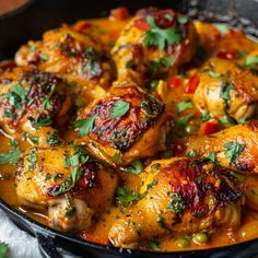 a skillet filled with chicken covered in sauce and garnished with cilantro