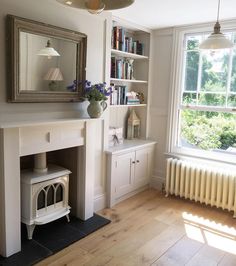 a living room filled with furniture and a fire place under a mirror on the wall