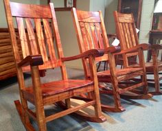 three wooden rocking chairs sitting on top of a carpeted floor next to each other