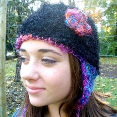 a young woman wearing a black hat with colorful crochet flowers on the brim