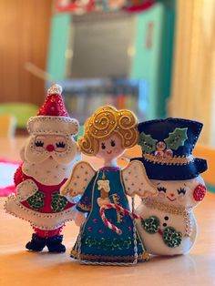 three snowmen are standing next to each other on a table in front of a christmas tree