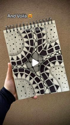 a hand holding up a spiral notebook with an abstract design