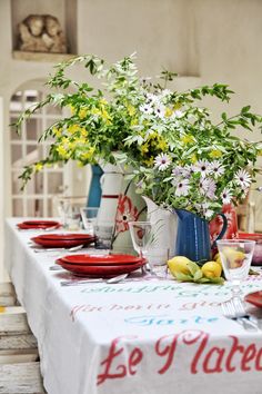 a table topped with plates and vases filled with flowers