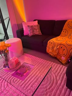 a living room filled with furniture and pink lighting on the walls, along with a coffee table