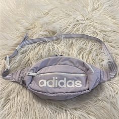 an adidas fanny bag laying on top of a fluffy white rug