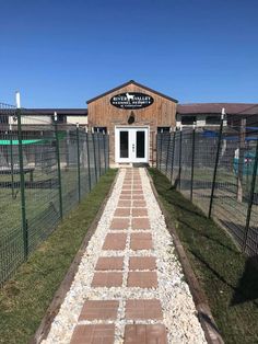 a building with a brick walkway leading to it and a fence surrounding the front door