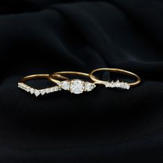 three gold rings with diamonds on black fabric