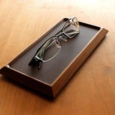 a pair of glasses sitting on top of a wooden tray