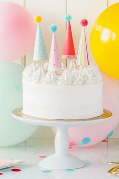 a birthday cake with white frosting surrounded by balloons