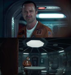 a man in an orange space suit standing next to a table