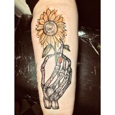 a tattoo on the arm of a person with a sunflower in it's hand