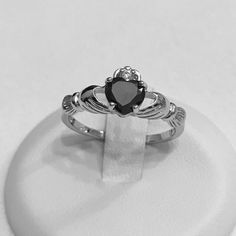 a cladder's heart ring sits on top of a white display stand with a black diamond