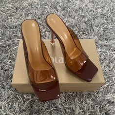 Complete your weekend vibe with these slip-on mules doll. Featuring a brown or red transparent color material with clear straps, these are sure to keep your weekend look effortlessly chic. Trendy Heels With Clear Strap, Trendy Brown Open Toe Mules, Trendy Brown Open Heel Heels, Trendy Brown Peep Toe Heels, Chic Heels With Transparent Straps, Brown Mules For Summer Parties, Brown Summer Party Mules, Brown Slip-on Party Heels, Brown Slip-on Heels For Party