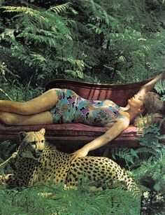 a woman laying on top of a bench next to a cheetah