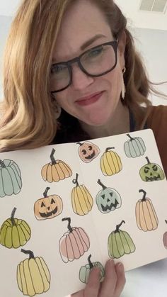 a woman holding up a book with pumpkins on it