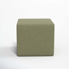 a green cube ottoman sitting on top of a white floor