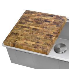 a large wooden cutting board sitting on top of a metal sink under a faucet