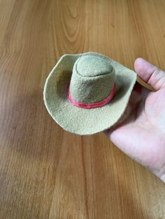 a hand holding a hat on top of a wooden table