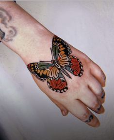 a woman's hand with a butterfly tattoo on it