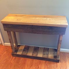 a small wooden table sitting on top of a hard wood floor next to a wall