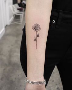 a woman's arm with a single rose tattoo on the left side of her arm