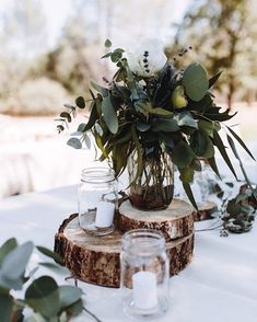 the table is set with mason jars, eucalyptus leaves and candles for an elegant centerpiece