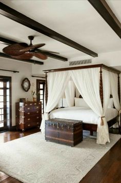 a bedroom with a canopy bed and white drapes