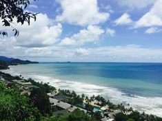 an ocean view from the top of a hill with houses on it and trees in the foreground