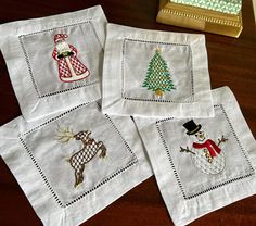 four embroidered christmas napkins on a table