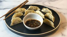 some dumplings are sitting on a plate with dipping sauce