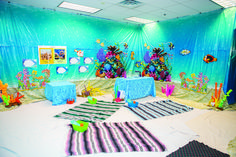 an underwater themed party with blue walls and decorations on the floor, including tables and rugs