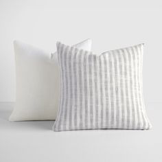 two white and grey striped pillows sitting next to each other