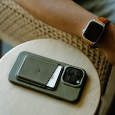 two cell phones sitting on top of a wooden table next to an apple watch case