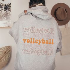 a woman wearing a hoodie with the words volleyball on it in orange and white