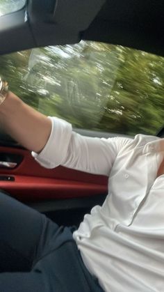 a man sitting in the driver's seat of a car with his hand on the steering wheel