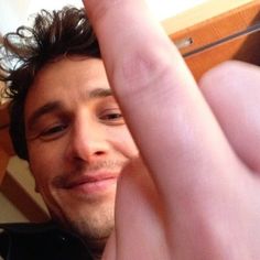 a close up of a person holding a doughnut in his hand and smiling at the camera