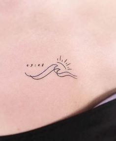 the back of a woman's stomach with a small wave tattoo on her left side