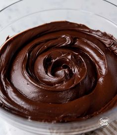 a glass bowl filled with chocolate frosting on top of a table