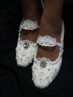 the bride's shoes are adorned with white lace and beaded embellishments