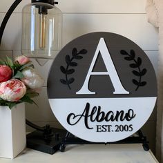 a black and white sign sitting on top of a table next to a vase with flowers