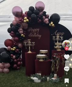 a birthday party with balloons, candles and decorations on the grass in front of a tent