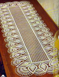 a table runner with white crocheted doily on it and yellow flowers in the background