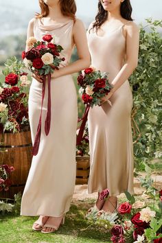 two women in long dresses standing next to each other holding bouquets and smiling at the camera