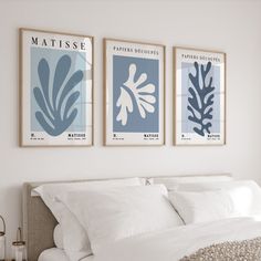 three blue and white posters on the wall above a bed