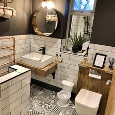 a white toilet sitting next to a sink in a bathroom under a large round mirror