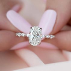 a woman's hand holding a ring with a large diamond in the center and two small diamonds on each side