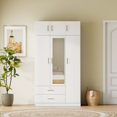 a room with a potted plant in the corner and two white cupboards next to it